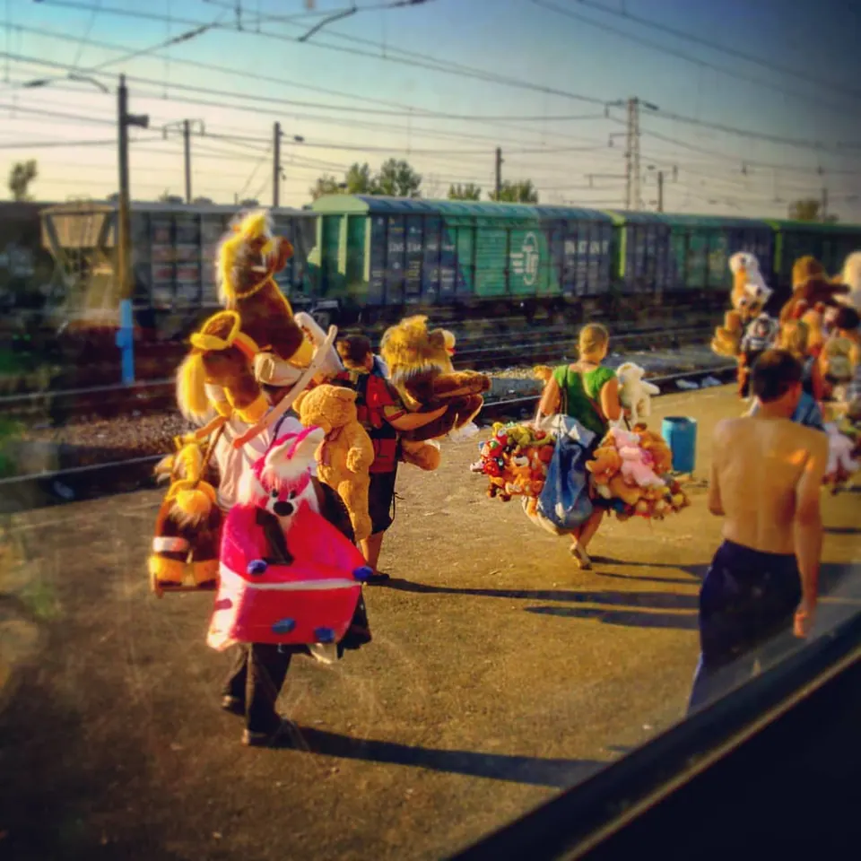 Brightly dressed figures move through a scene layered with reflections and colour.