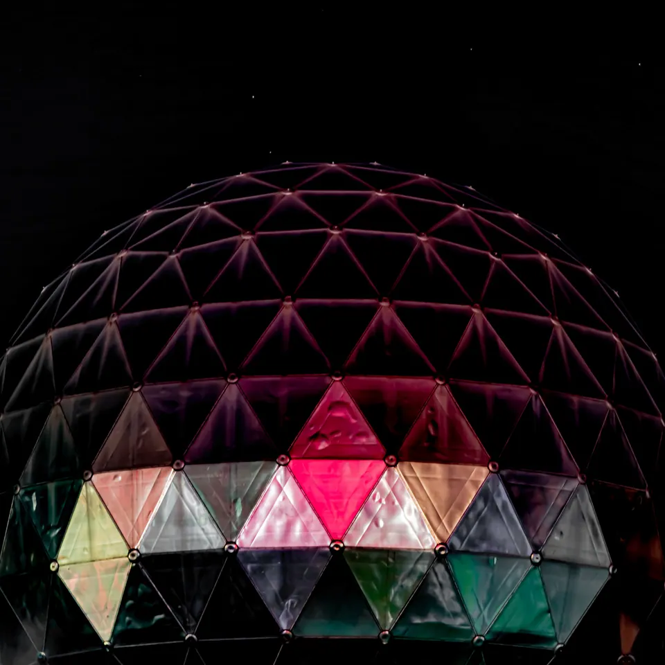 Coloured triangular panels form a glowing dome against the night sky.