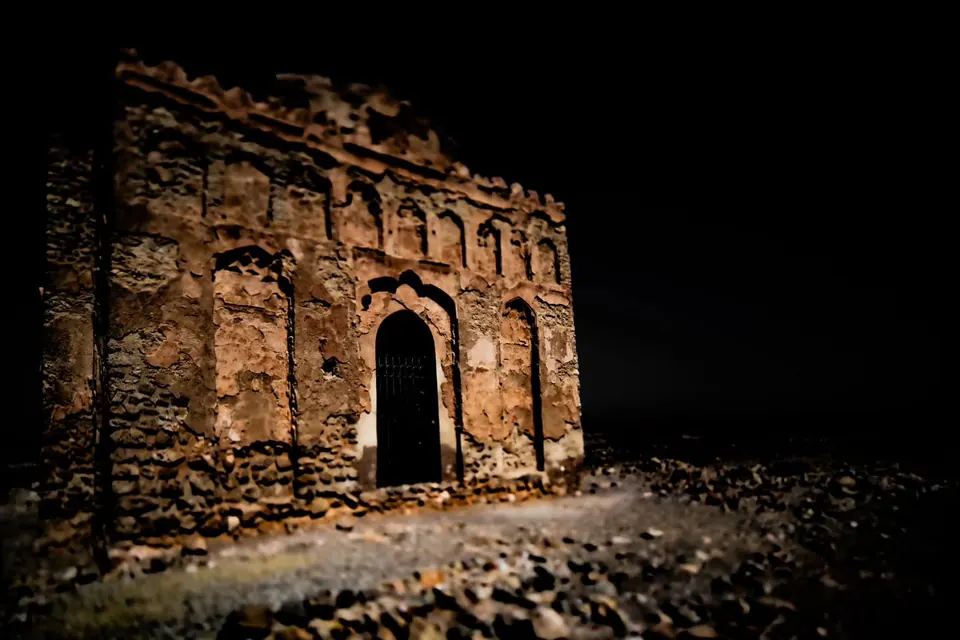 A shadowed doorway survives in a wall of rough, warm-coloured stone.