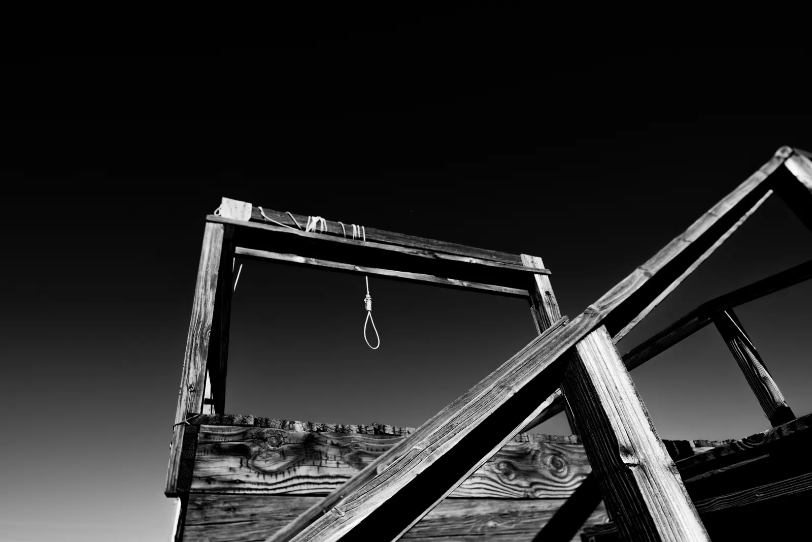 Broken wooden beams form sharp diagonals beneath an empty sky.