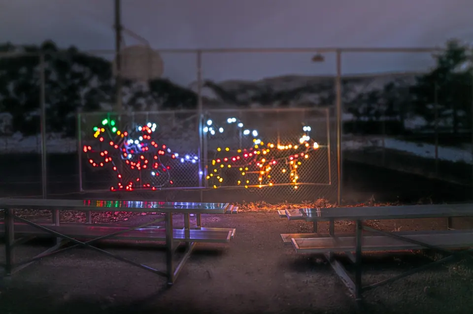 Coloured lights outline small shapes within a rectangular frame after dark.