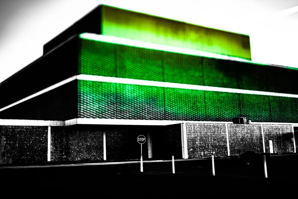 A vivid green strip crosses a dark, angular building facade.