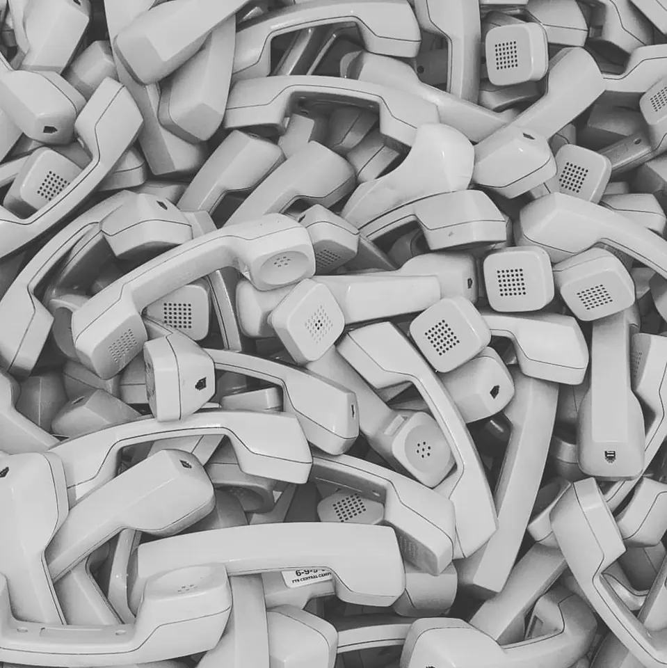 A dense pile of old small electronic devices fills the frame in black and white.