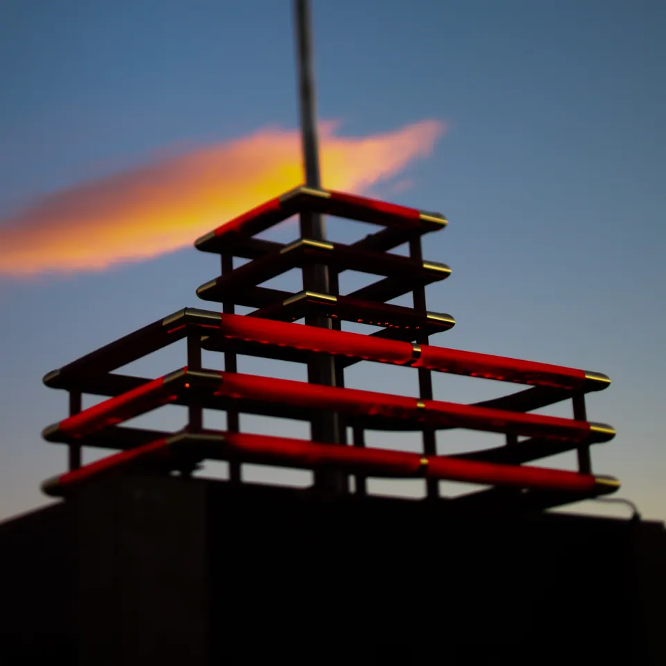 A stepped red structure is silhouetted beneath a single orange cloud.