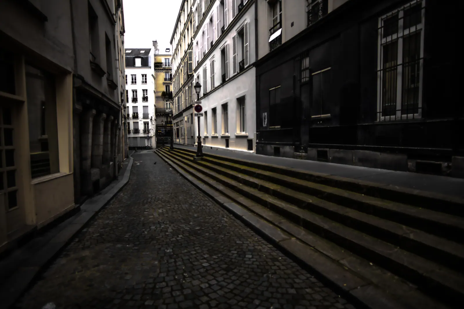 Tall buildings and stone paving frame an empty city street.