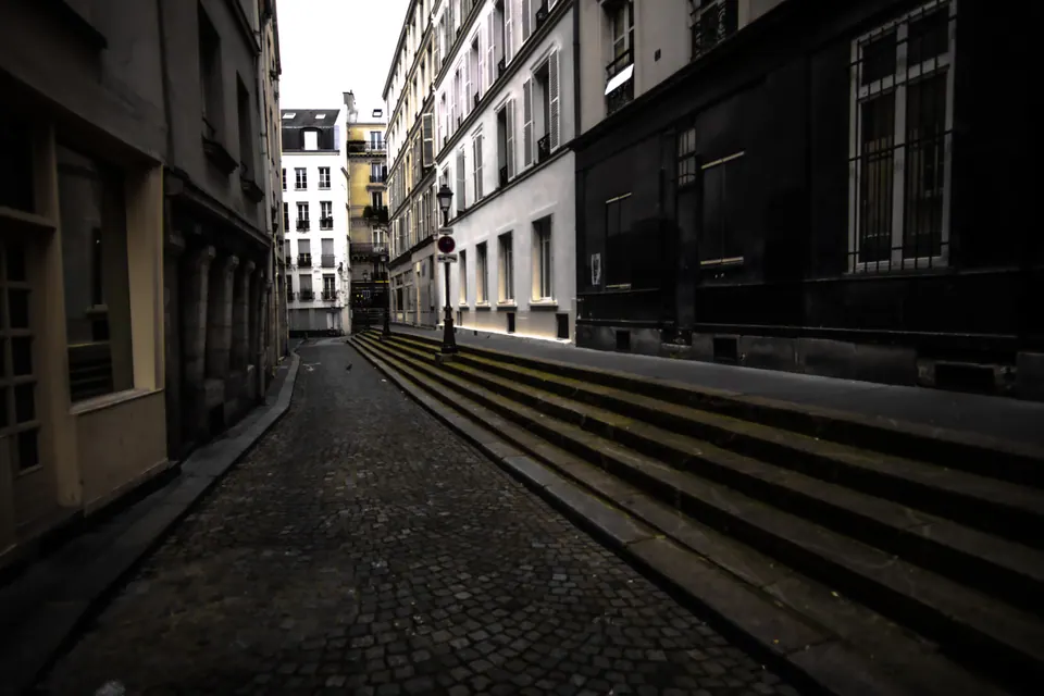 Tall buildings and stone paving frame an empty city street.