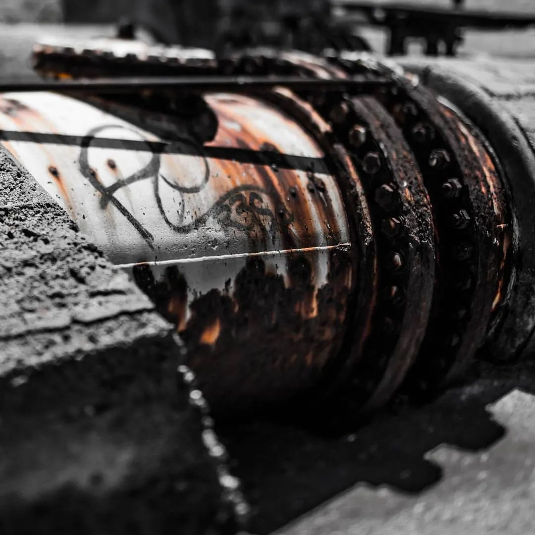 Rust, peeling paint and dark bolts mark a heavy piece of metal machinery.