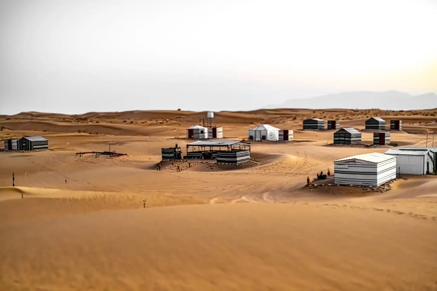 Low buildings and tracks sit among sweeping golden sand dunes.