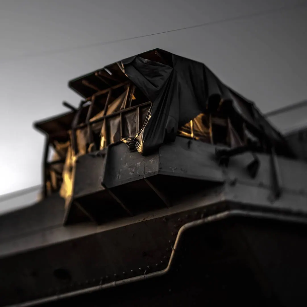 A dark geometric structure catches warm light above the edge of a building.