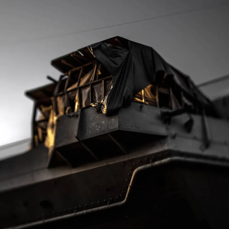 A dark geometric structure catches warm light above the edge of a building.