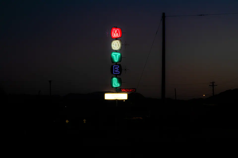 Vertically stacked MOTEL letters glow in red, green and blue against the evening sky.