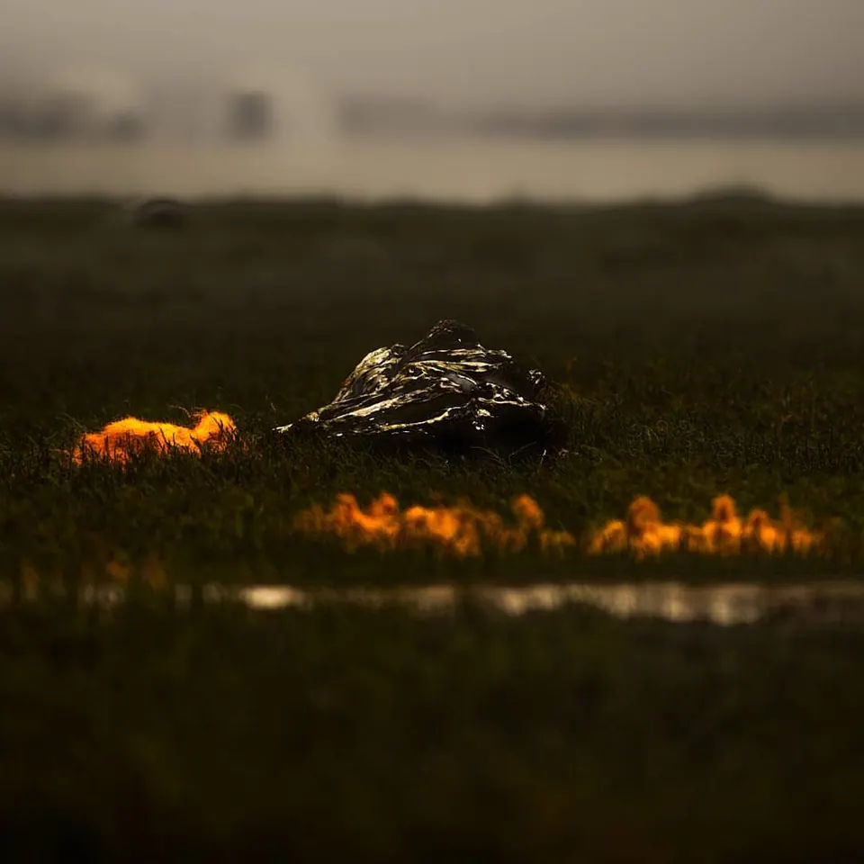 A low band of orange flame crosses a dark, softly focused landscape.