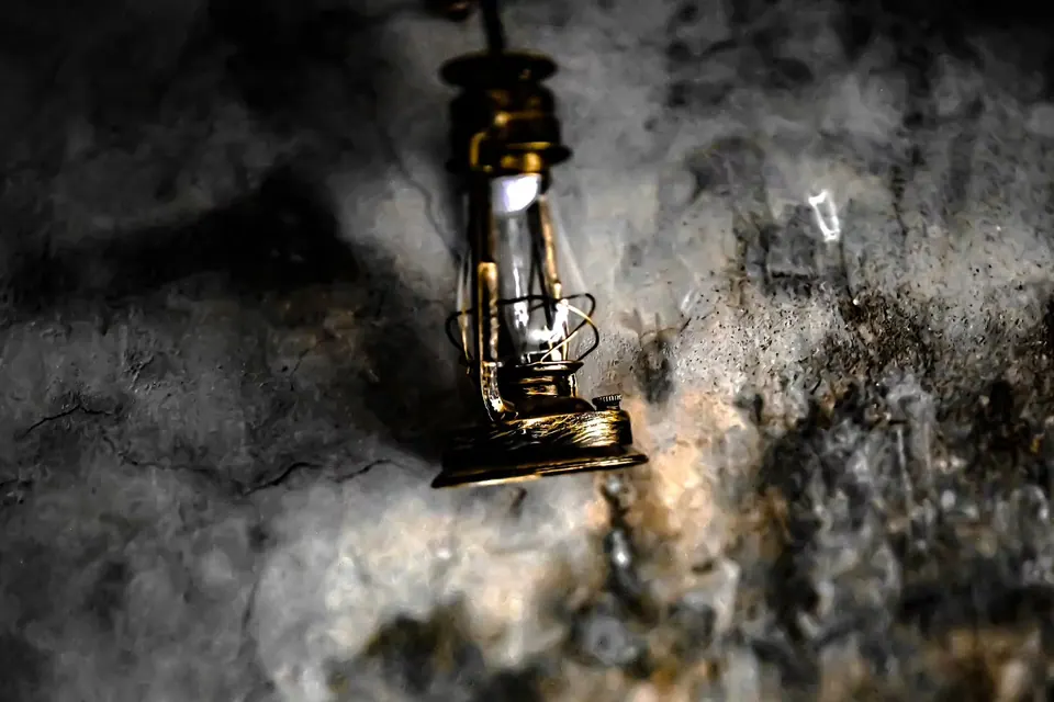 A weathered lantern rests against a rough wall in a pool of warm light.