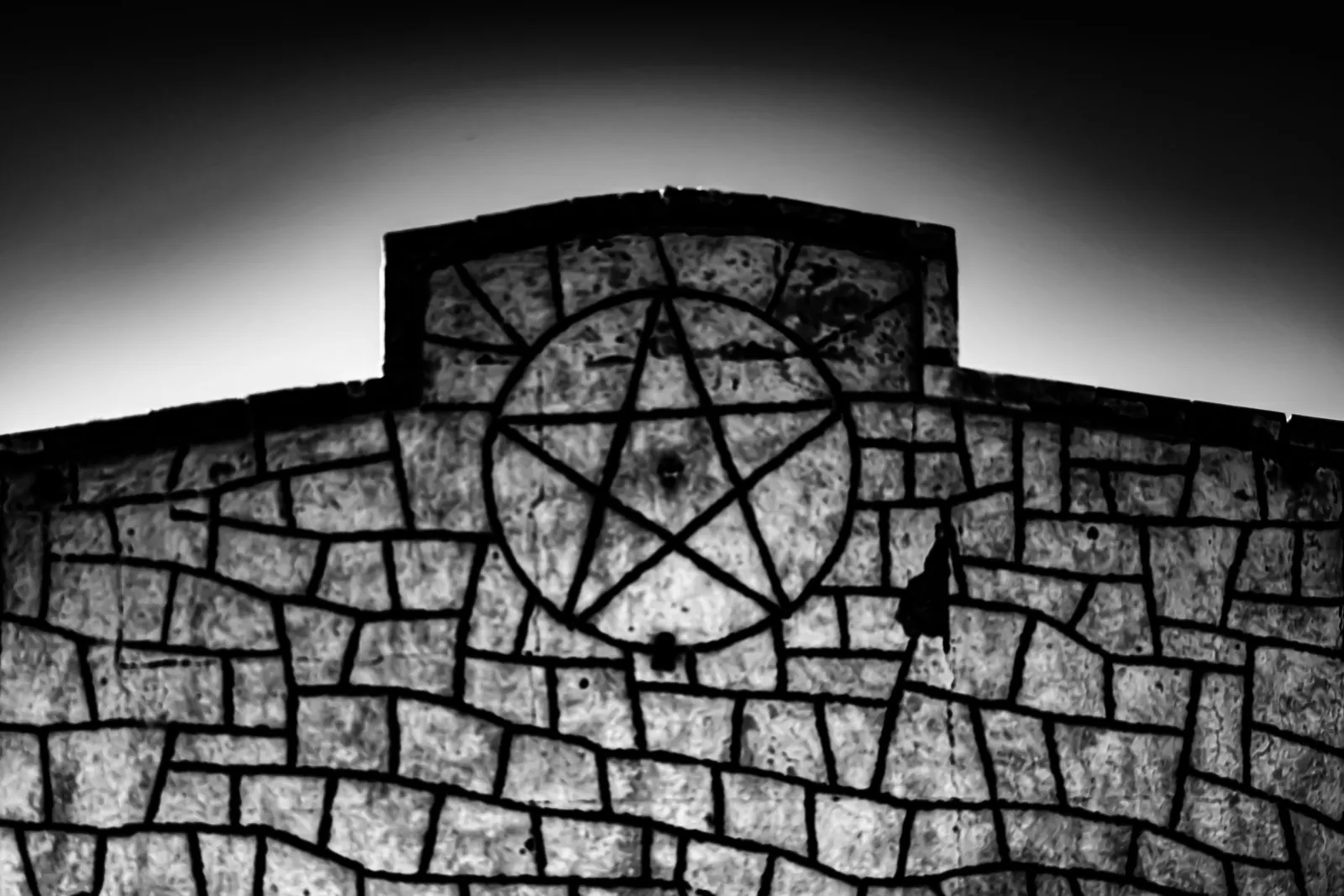 A dark metal star sits within the stonework above an old doorway.