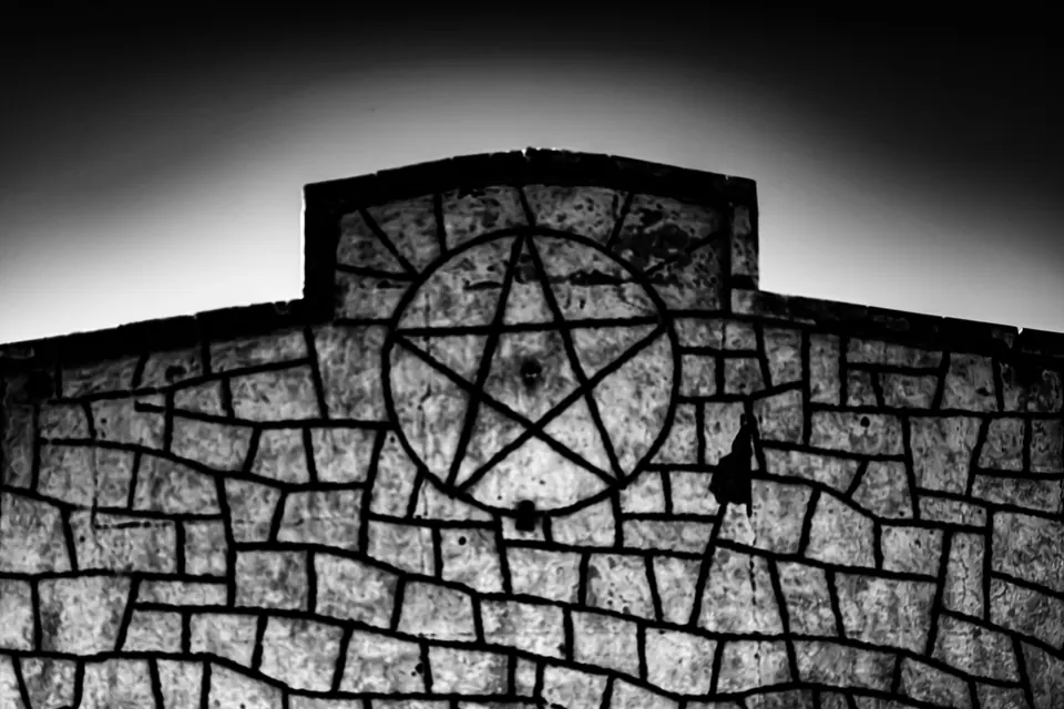 A dark metal star sits within the stonework above an old doorway.