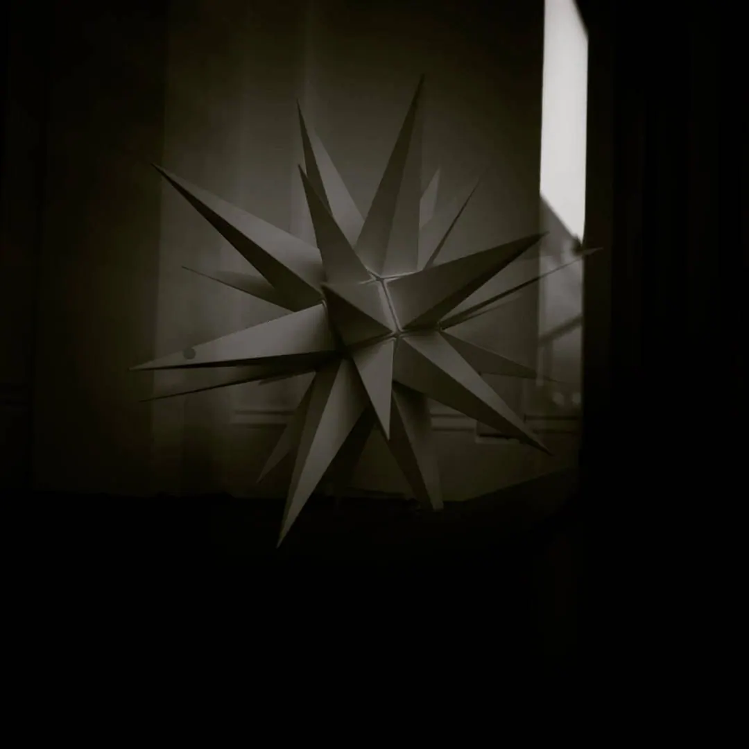 A many-pointed star hangs in a softly lit window above a dark interior.