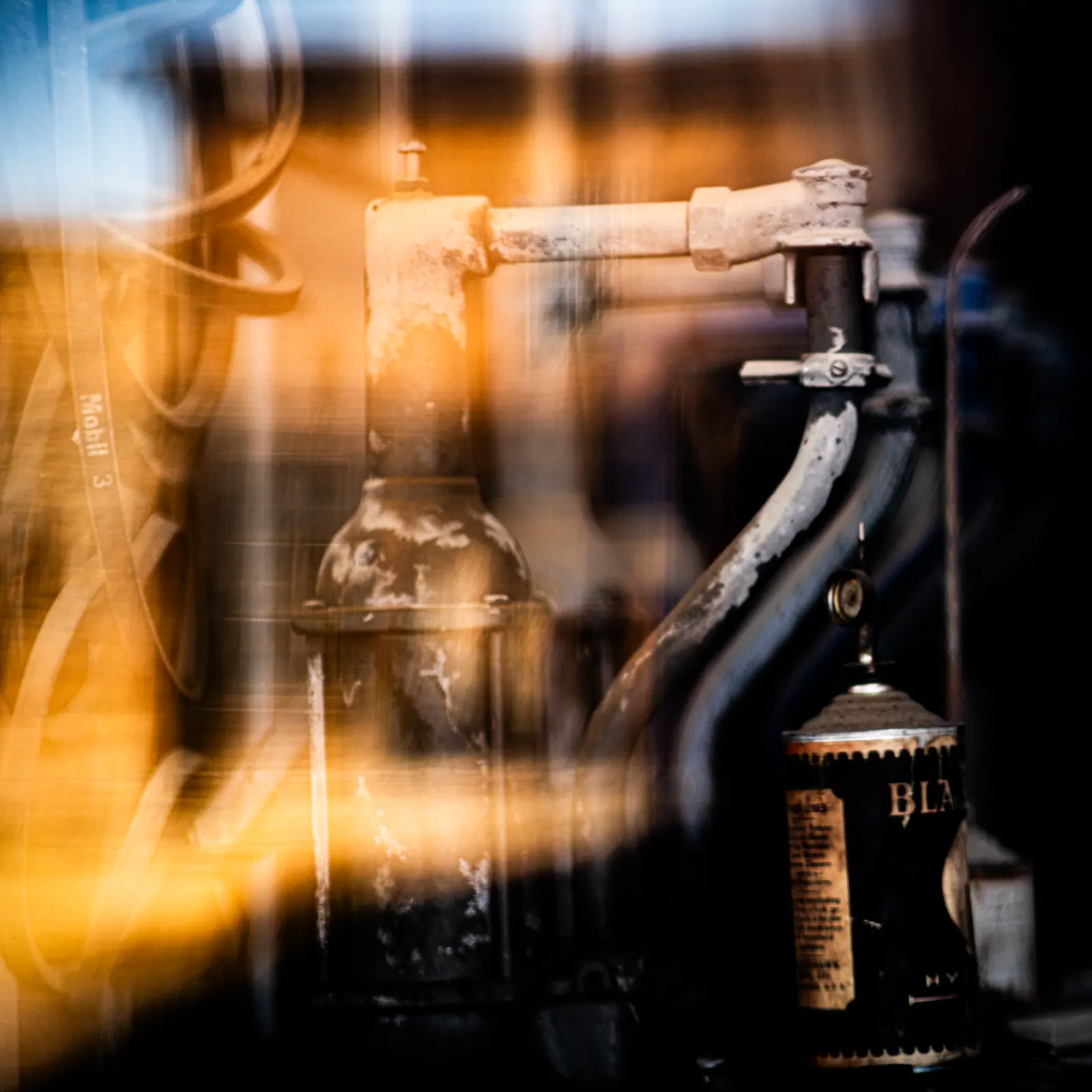 An old metal tap is framed by blurred glass and warm reflections.