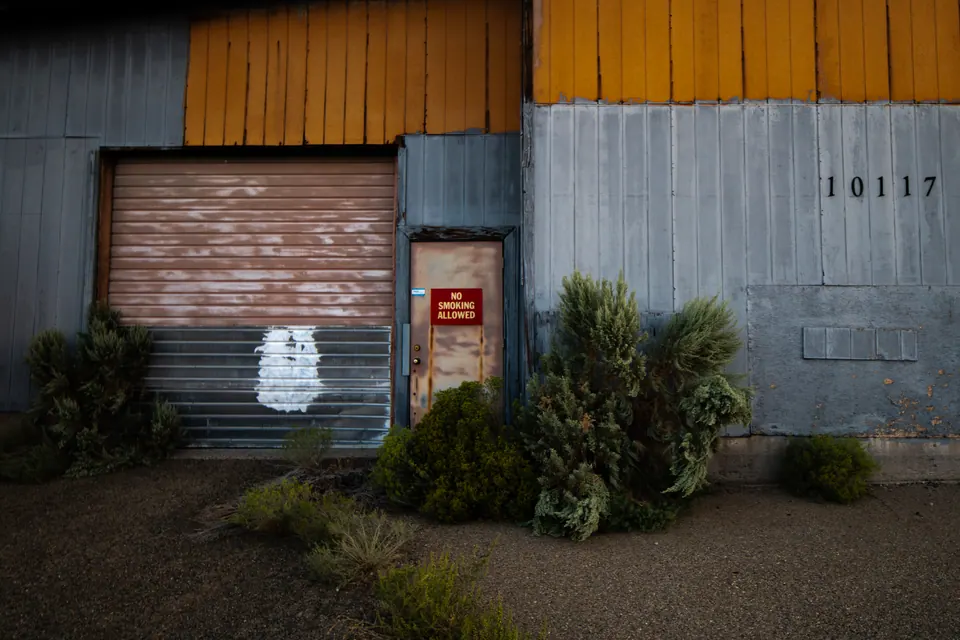 An orange and grey industrial wall surrounds a closed door and rolling shutter.