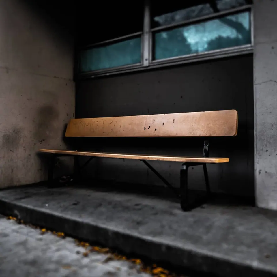 A wooden bench waits against a wall beneath a darkened window.