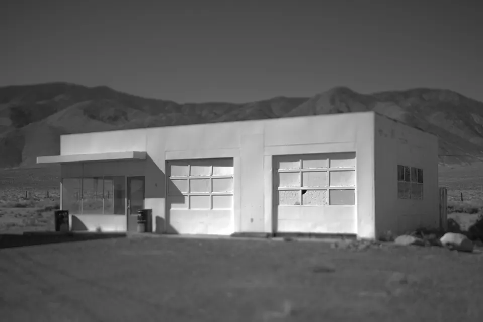 A low white service-station building sits against dark desert mountains.