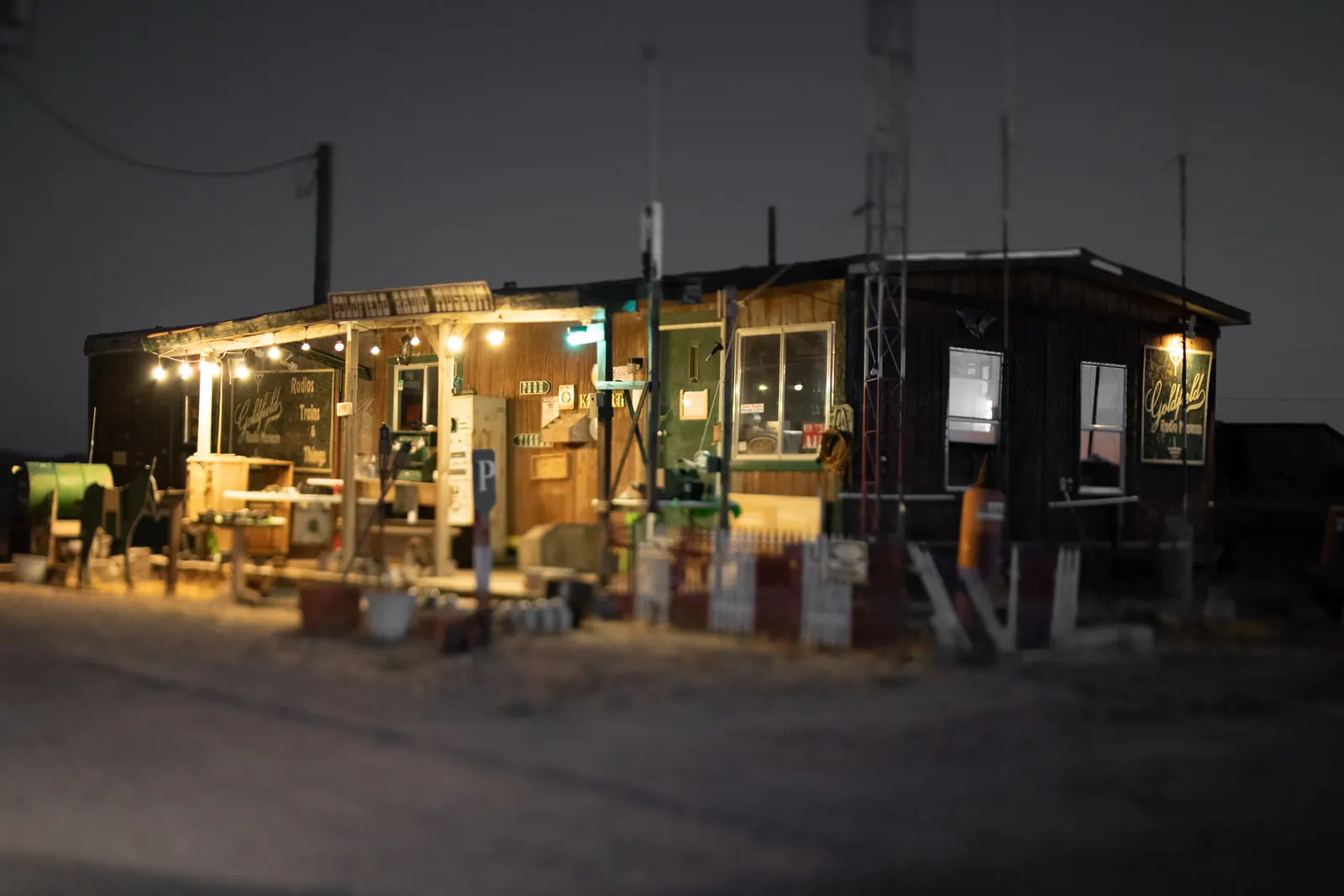 Warm lights illuminate a small roadside business against the night sky.
