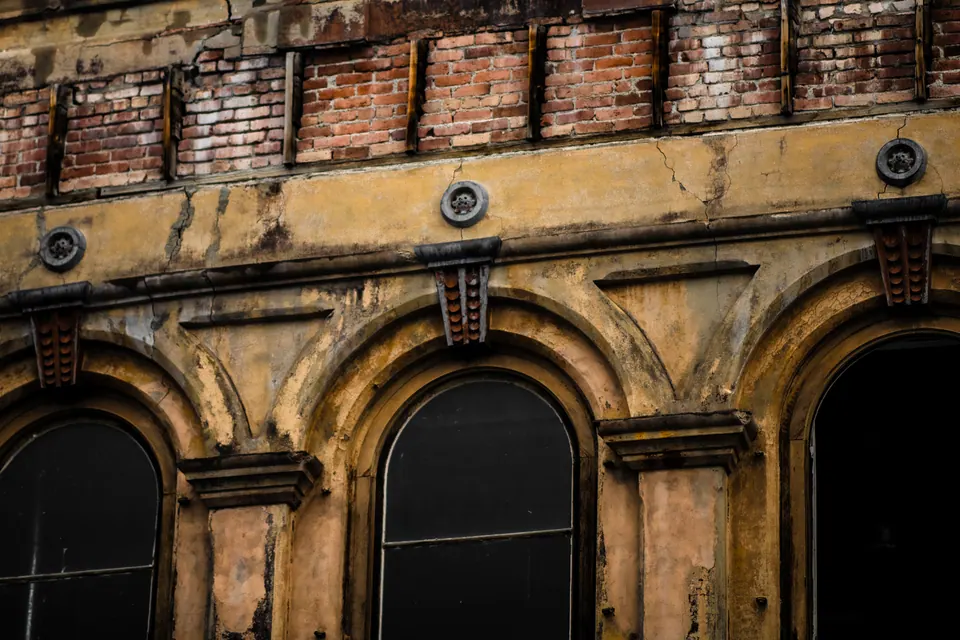 Three arched openings and a row of old bricks catch warm light.