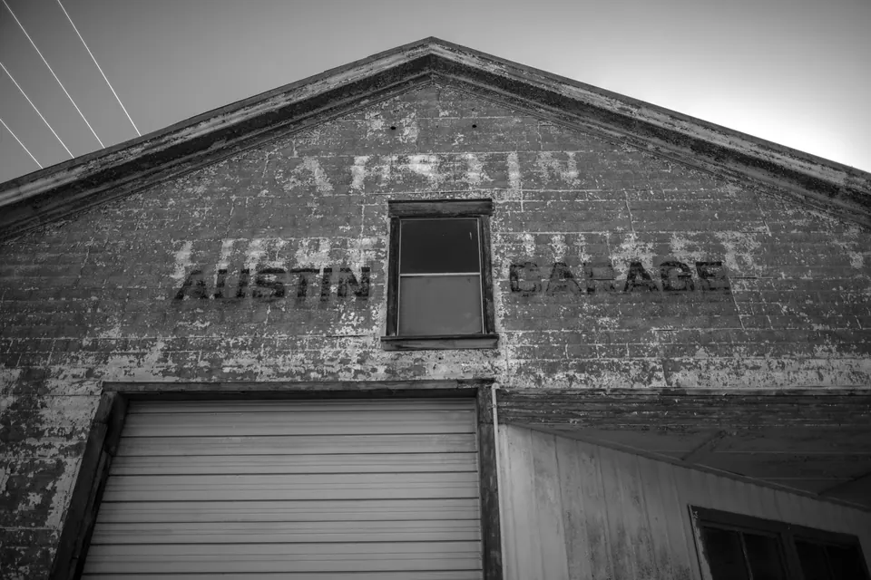 Faded lettering sits above a closed garage door in an old brick facade.