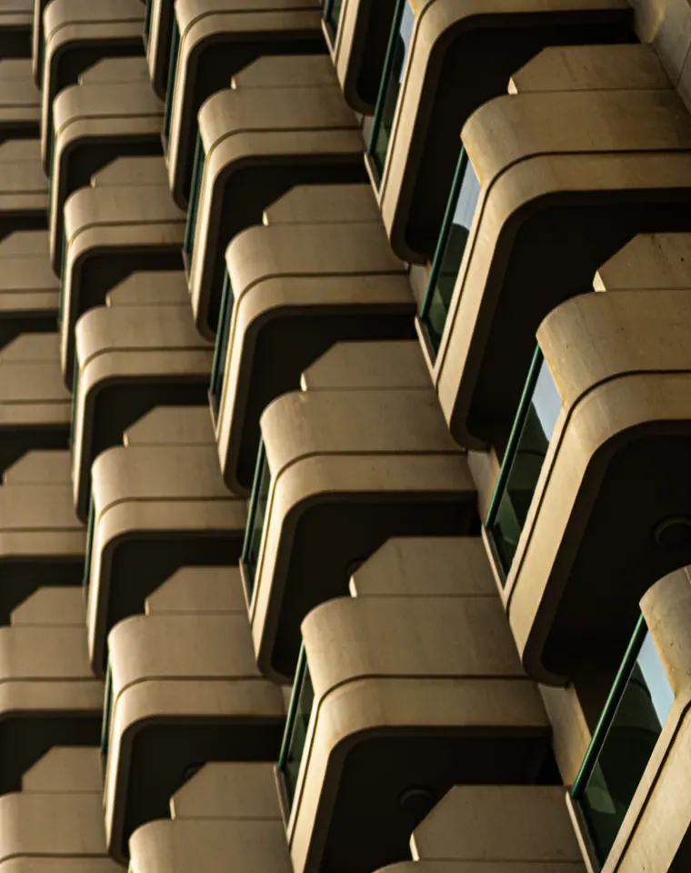 Curving balconies repeat up a building facade in alternating light and shade.