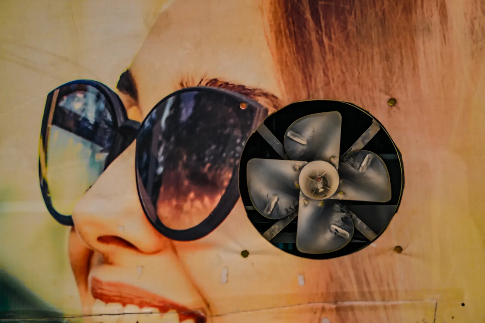 An advertisement showing a face in dark sunglasses is interrupted by a circular vent.