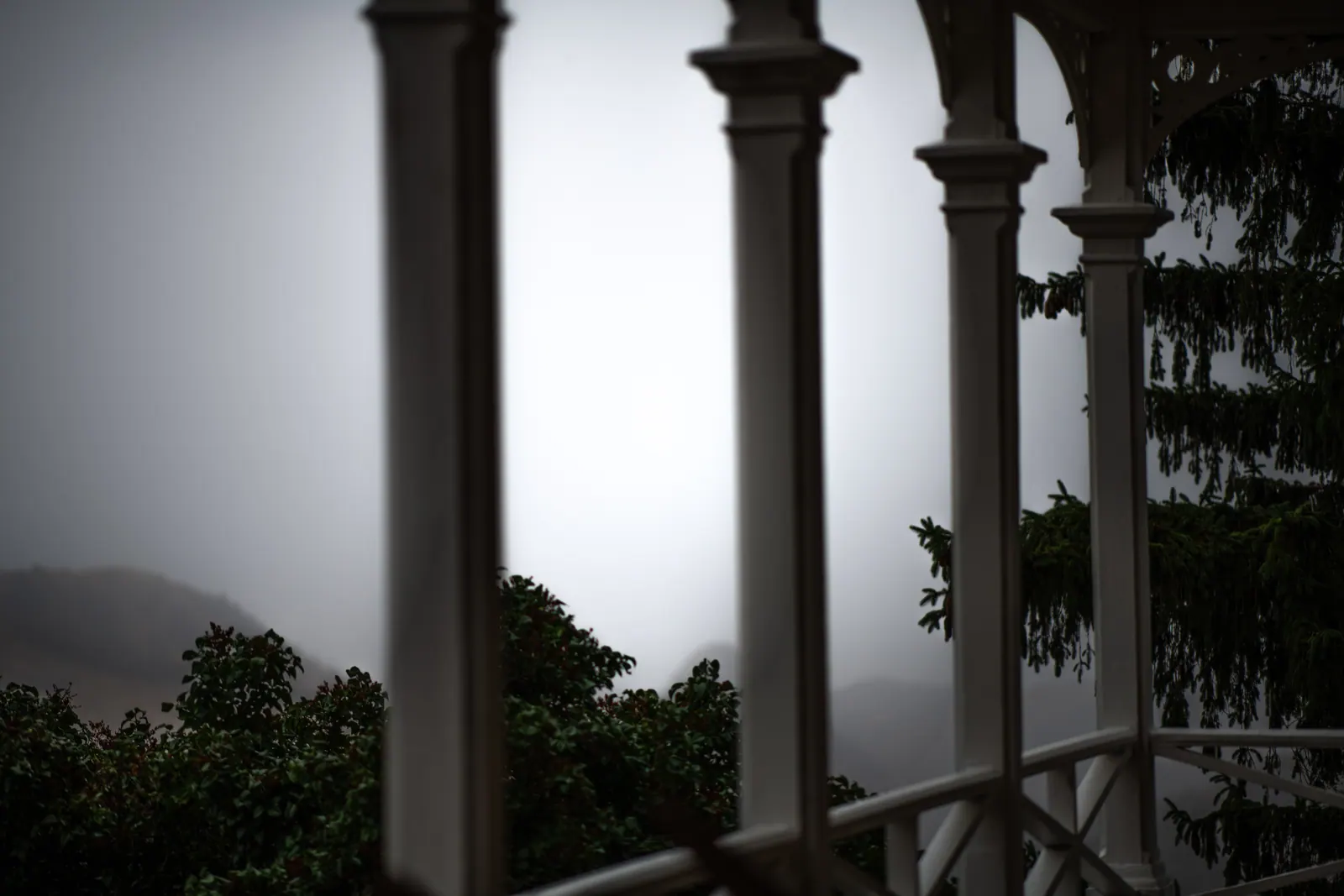 Porch columns frame a softly blurred view of hills and trees.