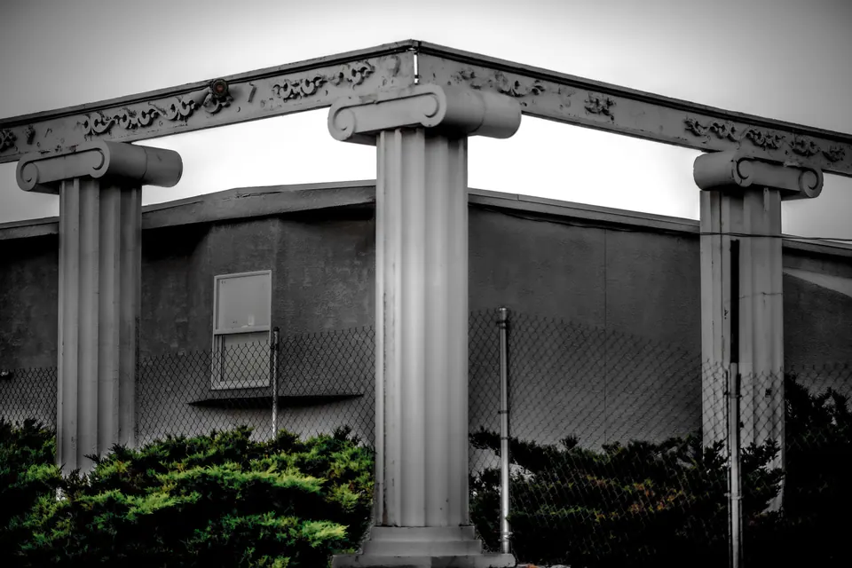 Pale decorative columns frame the corner of a quiet building.
