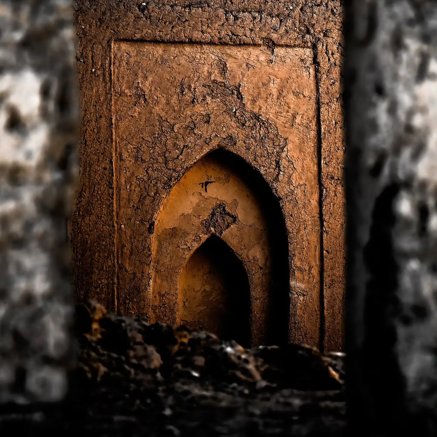 A pointed doorway opens into the dark interior of an earthen building.