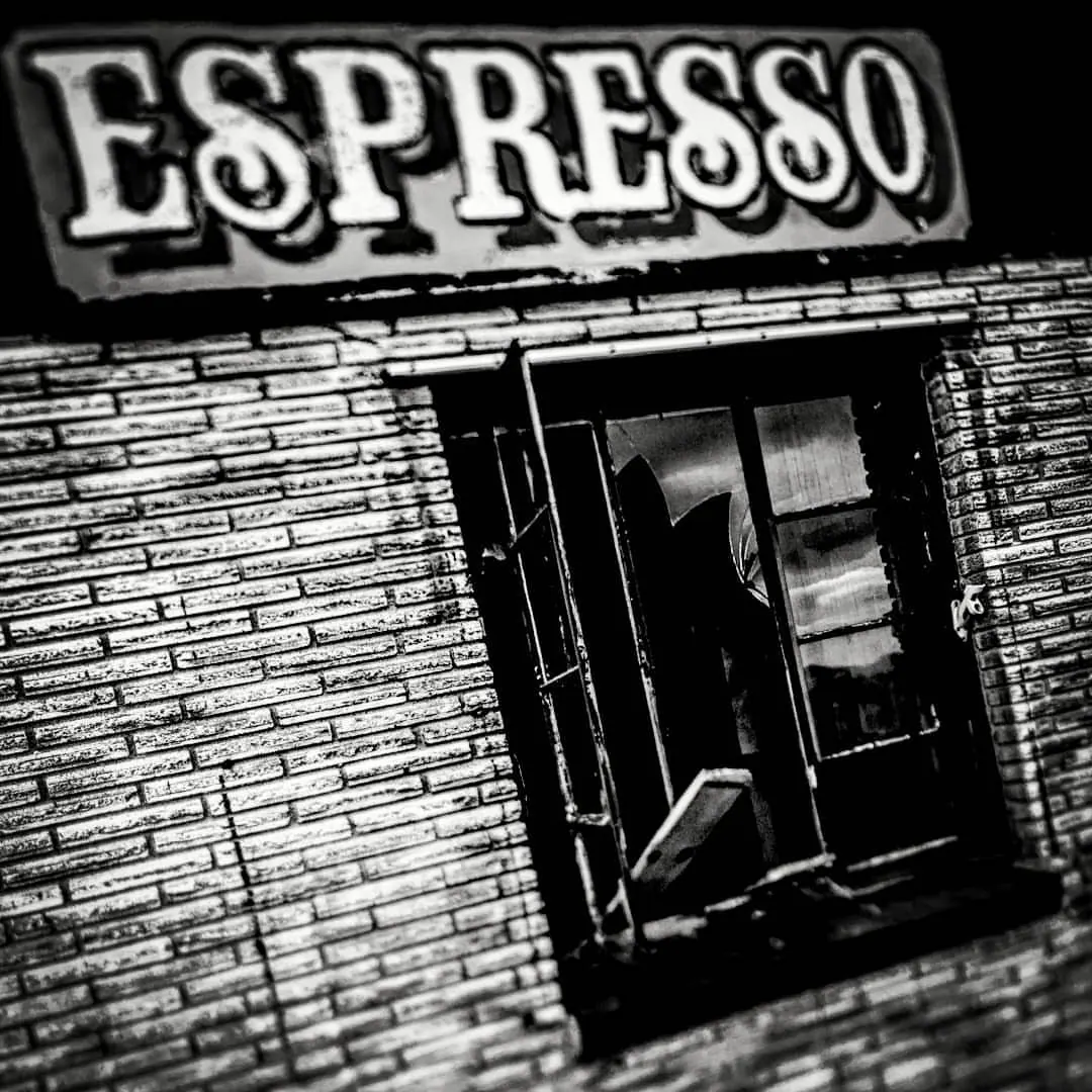 Bold Espresso lettering hangs above a dark doorway in a brick facade.