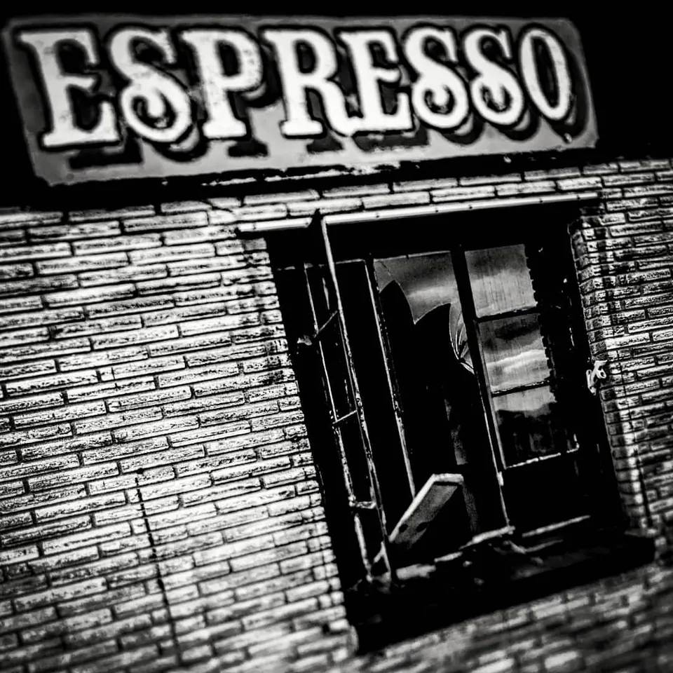 Bold Espresso lettering hangs above a dark doorway in a brick facade.