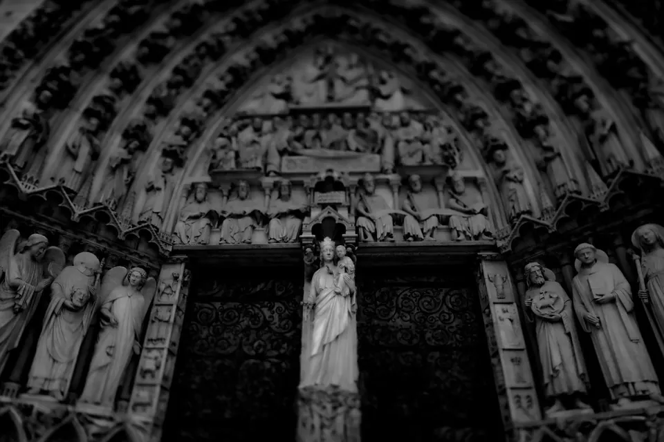 Carved figures surround the dark entrance of a cathedral in black and white.