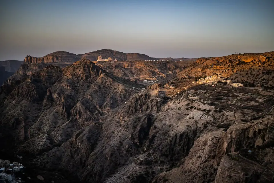 Warm light reveals the layered texture of a rugged mountain range.