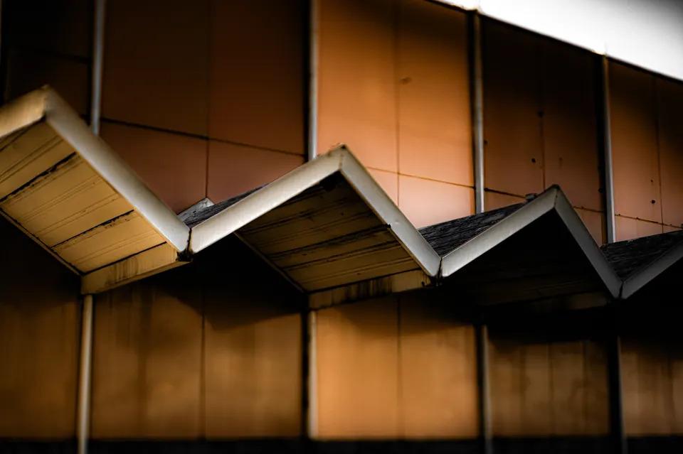 Angular roof edges cast deep shadows across an ochre building facade.
