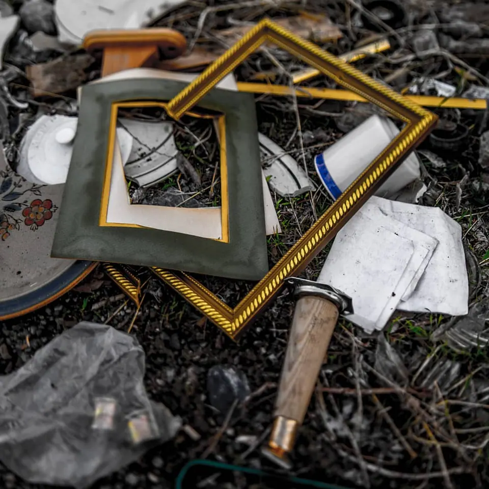Empty gold-coloured picture frames lie among broken masonry and scattered objects.