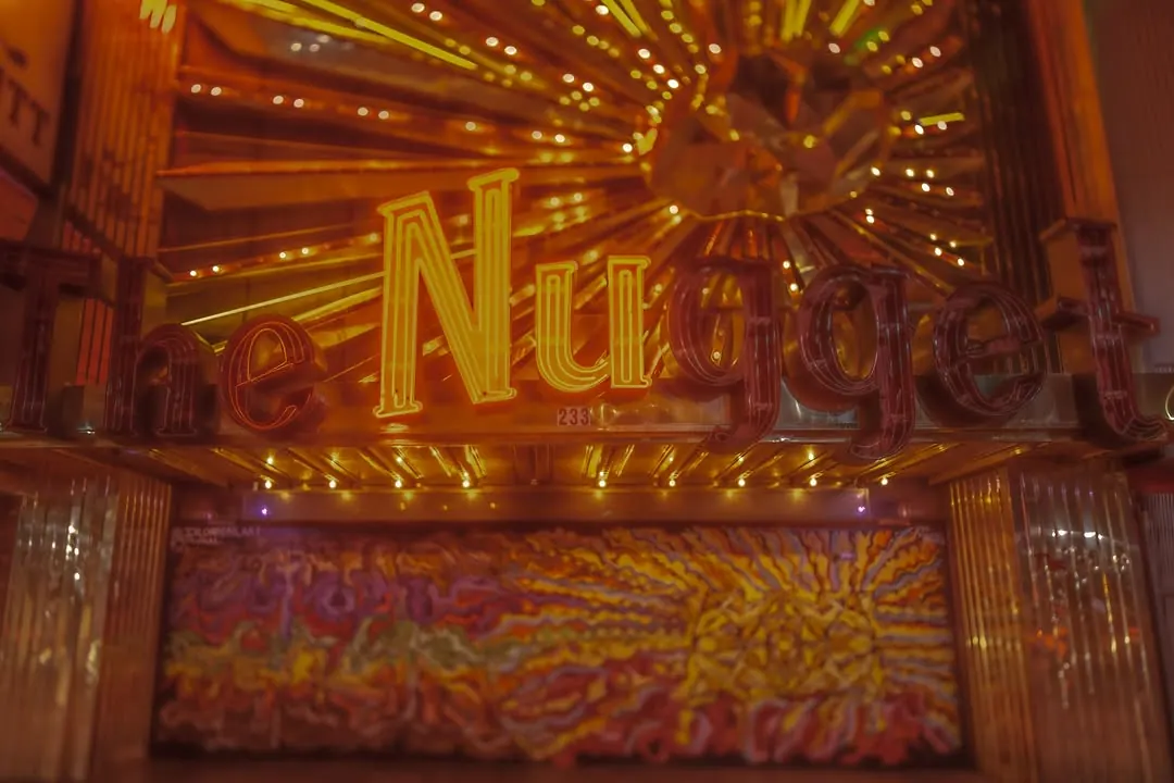 Warm bulbs and golden lettering fill a casino window after dark.