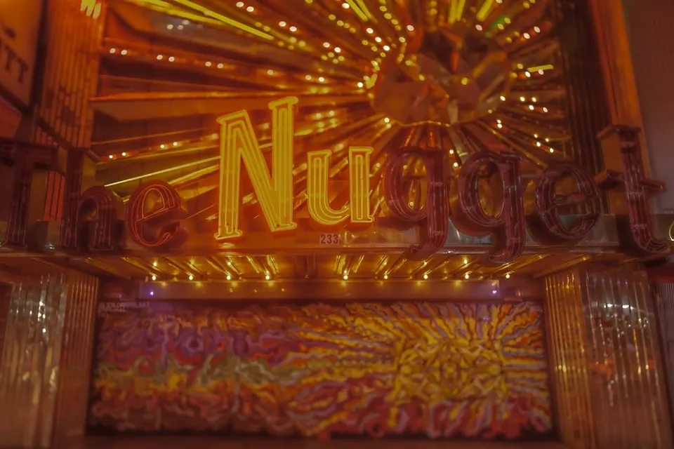 Warm bulbs and golden lettering fill a casino window after dark.