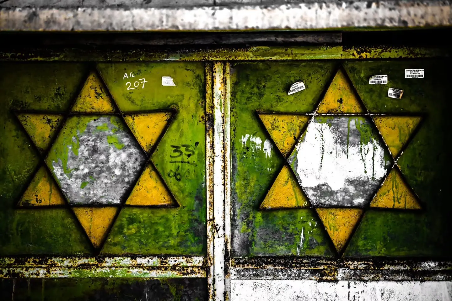 Faded star-shaped designs cover a pair of weathered green metal doors.