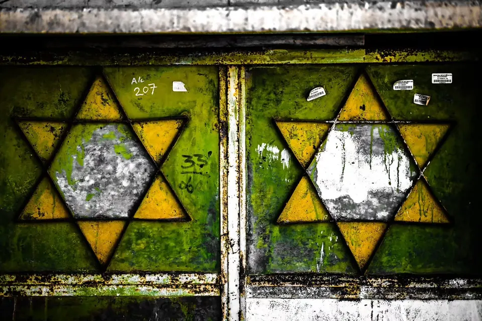 Faded star-shaped designs cover a pair of weathered green metal doors.