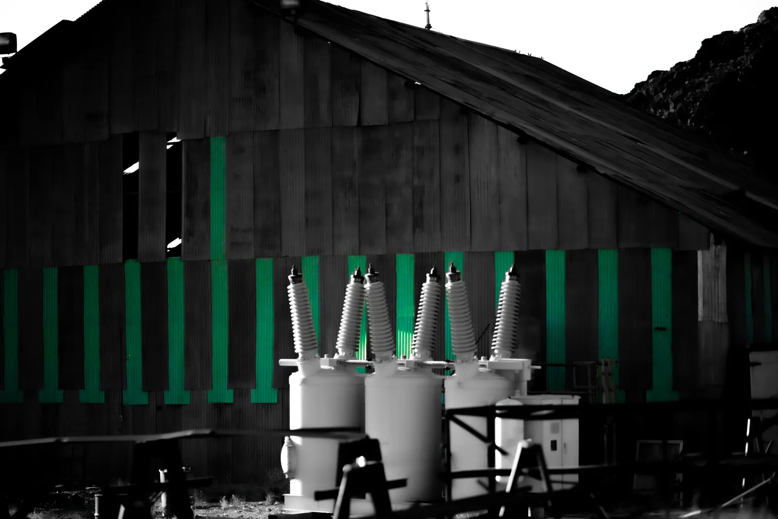 Green vertical slats and pale utility equipment stand against a dark wooden wall.