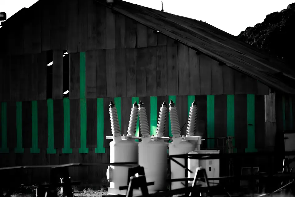 Green vertical slats and pale utility equipment stand against a dark wooden wall.