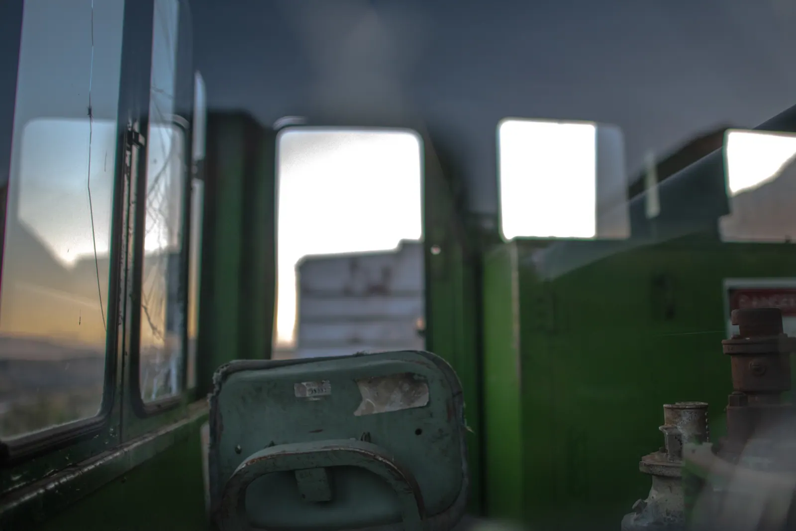 Green seats and faded panels line the interior of an old railway carriage.