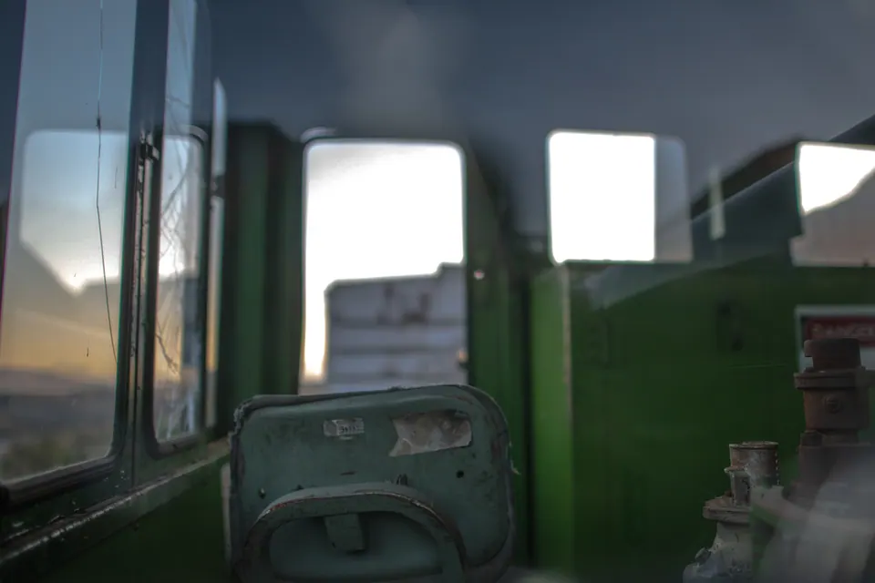 Green seats and faded panels line the interior of an old railway carriage.