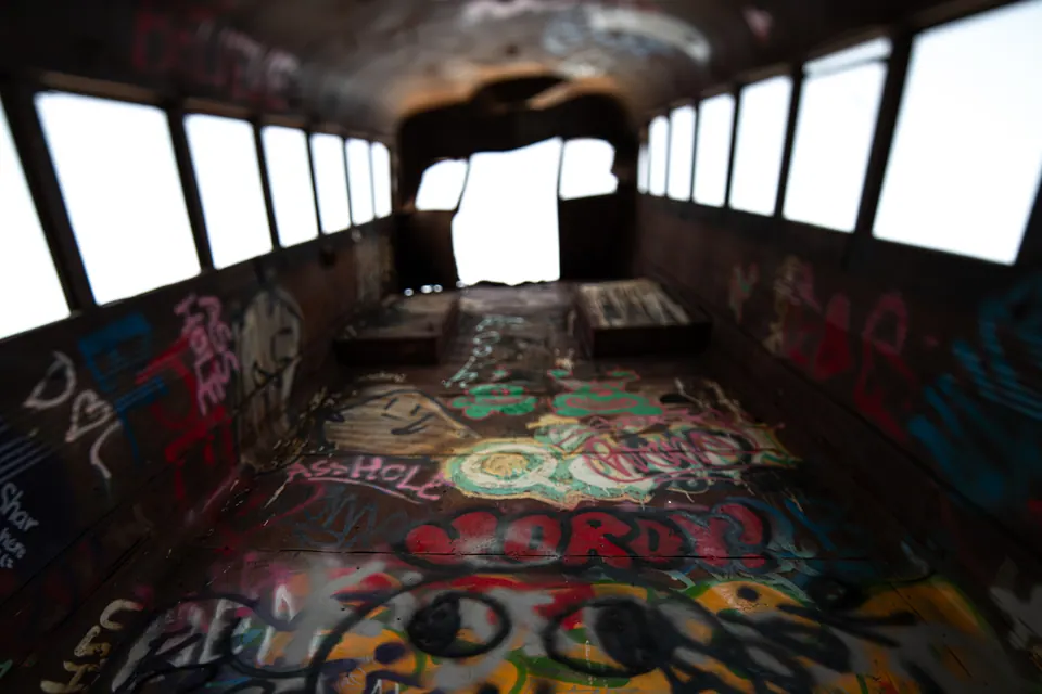 Graffiti covers the floor and windows of an abandoned bus.