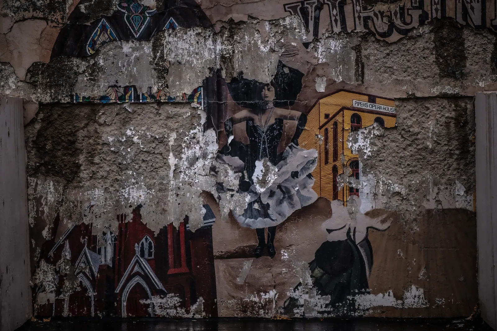Torn posters and fragments of painted imagery overlap on a weathered wall.
