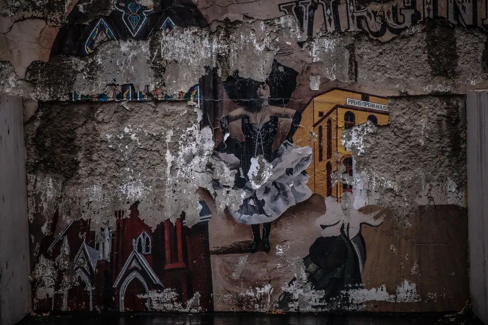 Torn posters and fragments of painted imagery overlap on a weathered wall.
