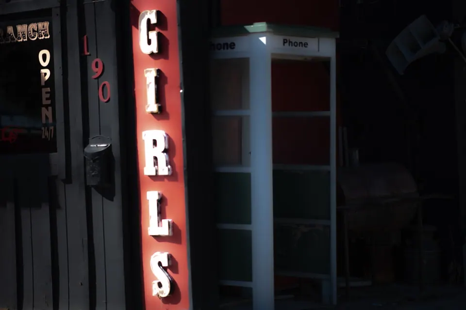 Glowing red letters run vertically down the side of a dark building.